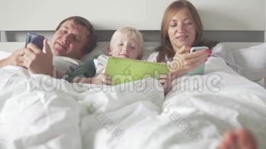 一家人带着孩子<strong>躺在床上</strong>，<strong>床上</strong>有平板电脑和手机