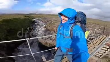 微笑青年男子徒步穿越崎岖的冰岛地形，在Fimvorduhals上，大风达到每秒30米