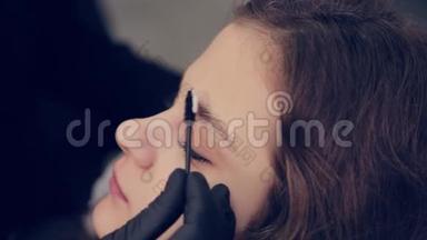 专业大师眉毛女士在美容院给客户梳眉毛。