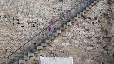 一个女孩走上台阶，来到一座古老建筑的观景台。 法马古斯塔堡