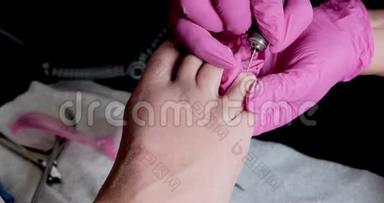 带粉色手套的教育学大师是用钻头在修脚沙龙切割角质层和紫胶脚趾甲。 专业教育
