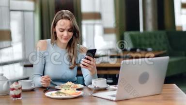 笑的女孩吃着美味的晚餐，在自助餐厅滚动社交网络。 中型摄影机