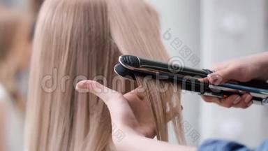 用烫铁工具把女理发师弄直金发。 近距离拍摄4k红色相机