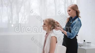 女理发师从女客户的时尚发型中拔出理发师。 中型<strong>摄影机</strong>