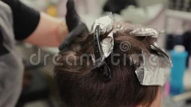 专业的理发师女染发女孩`她的头发与染发箔。