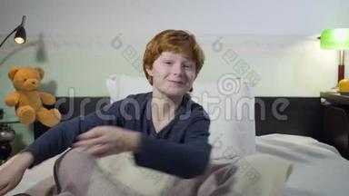 可爱的白种人小男孩的头像<strong>切换</strong>频道，作出感兴趣的面部表情，并看电视。 红头发