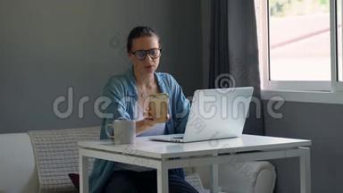 戴眼镜的年轻严肃的女人在电脑里工作。 感觉很累。