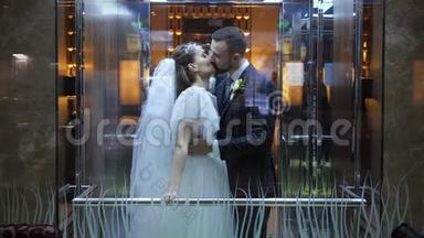 在乌克兰哈尔科夫宫酒店的电梯里<strong>亲吻</strong>婚礼快乐的夫妇。 有胡子的新郎拥抱并<strong>亲吻</strong>他
