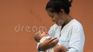 幸福的亚洲母亲抱着他刚出生的可<strong>爱婴</strong>儿穿衣服的肖像。 妈妈用<strong>爱</strong>和关怀拥抱她的孩子。 她