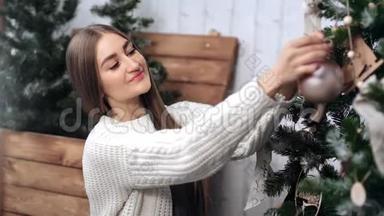 漂亮的女人把玩具球挂在圣诞树上。 中型近距离拍摄4k红色相机