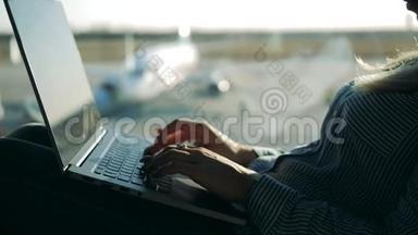 机场窗户旁的一位女士正在操作笔记本电脑