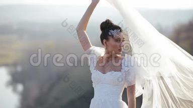 美丽的新娘穿着<strong>豪</strong>华的白色<strong>礼</strong>服，站在风清秋的荒芜的田野里，向她挥动面纱