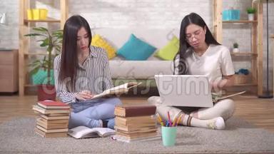 两个可爱的亚洲学生正坐在书和笔记本电脑旁边的地板上准<strong>备考</strong>试