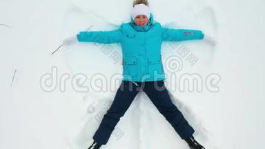 一个女孩在森林<strong>的</strong>空地上做一个<strong>雪天</strong>使<strong>的</strong>身影。 一个女孩躺在雪地里<strong>的</strong>空中摄影。