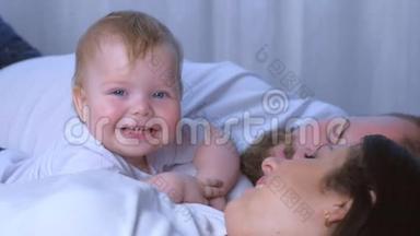 一岁的孩子微笑<strong>着看着</strong>和父母<strong>躺</strong>在一起的相机的肖像。