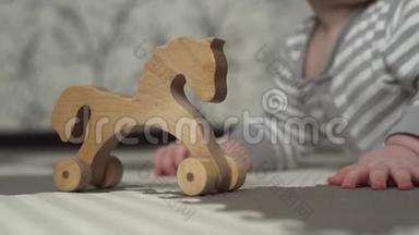木制玩具马站在地板上。 背景中，一个穿着灰白色条纹睡衣的小孩子正在玩耍..