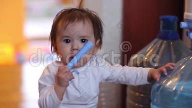 小女孩坐在尿布里，拿着一大瓶饮用水，微笑着给五个张开的手标志。