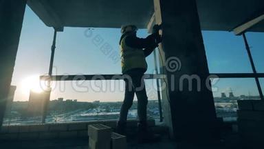 男建造师正在建筑工地打磨一根柱子
