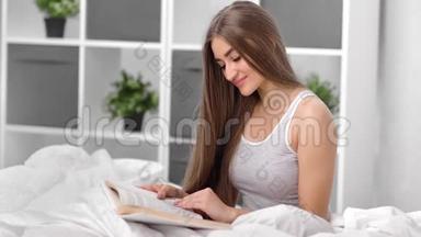 坐在床上享受休闲阅读书籍的国内美女。 中型摄影机