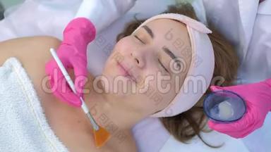 美容医生用刷子在美容诊所`妇女脸上<strong>敷面膜</strong>。