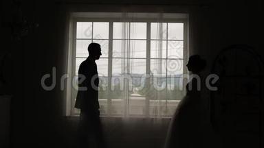 新郎遇见新娘。 新婚夫妇拥抱亲吻站在窗边