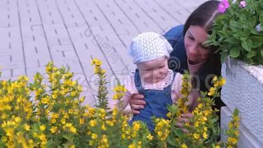 妈妈和女儿宝宝在公园里散步，抱着她看着花。