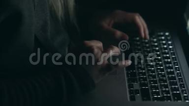 头罩里的黑客在暗室里用笔记本电脑打字。