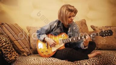 女孩在<strong>沙</strong>发上弹吉他。女人在室内创作<strong>音乐</strong>。这位艺术家用低音吉他演奏。<strong>音乐</strong>家作曲