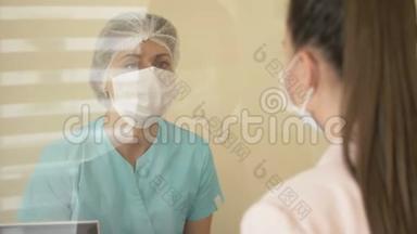 在医院候诊室，<strong>值班</strong>护士正在与病人交谈。 护士和病人戴医用口罩