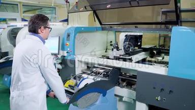 工程师穿着白色长袍和眼镜为表面安装技术机器工作。 数控<strong>机床</strong>PCB加工