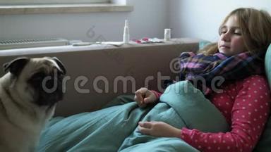 生病的小美丽的女孩带着围巾和她的狗在床上。 女孩身边有药品：喷鼻剂