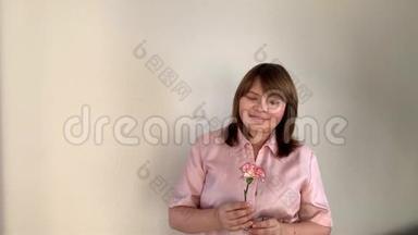女人捧着一束粉红色的康乃馨花，开心地笑着，节日的概念，情人节`，妈妈