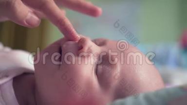 妈妈用过敏霜或其他皮肤病润滑婴儿脸，婴儿皮肤上的一个白斑。 皮肤护理