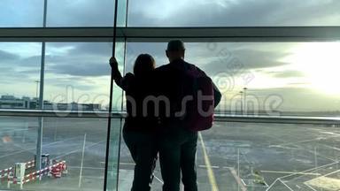 两名游客，一男一女，背着背包，站在机场休息室，<strong>望</strong>着<strong>窗外</strong>，旅行理念