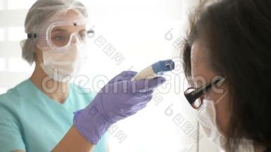 戴着医用口罩、眼镜和手套的护士用非接触式红外温度计测量病人的体温。