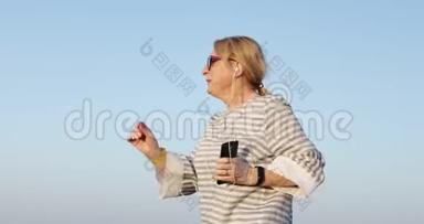 六十岁的快乐女人戴着耳机做早操。