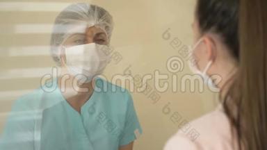 在医院候诊室，<strong>值班</strong>护士正在与病人交谈。 护士和病人戴医用口罩。 病人