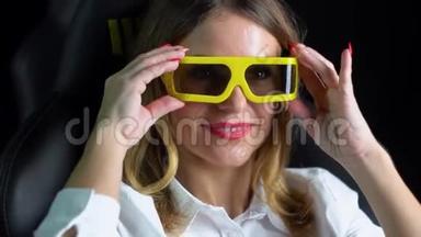 一个女人戴上3D眼镜。 女人在电影院看激动人心的电影，戴着3D眼镜