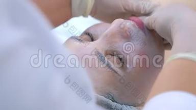 美容师用保湿面膜做面部按摩`女人的脸。