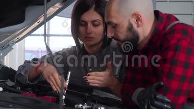 两名专业技工男女在汽车修理厂修理一辆汽车。 汽车服务、维修和<strong>保养</strong>