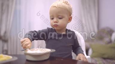 食物和饮料-儿童饮食概念。 小男孩在厨房吃早餐。 快乐的小男孩勺子吃自己。