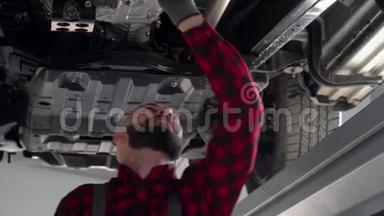 大胡子修理工在汽车修理厂修理一辆汽车. 汽车服务、维修和保养