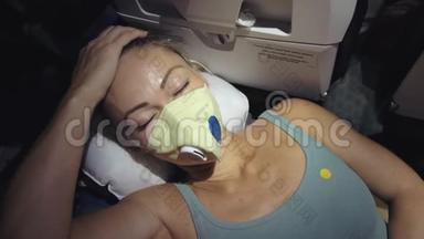 女人在飞机上旅行白种人，戴着防护医疗面罩。 带呼吸器的飞机上的女游客，<strong>感觉不好</strong>