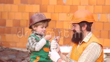 小儿子工人竖起砖墙。 男孩扮演建筑工或修理工。 儿子帮手。 孩子对未来职业的梦想