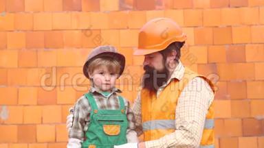 儿子和<strong>父亲</strong>放一块砖来建一堵墙。 男孩扮演建筑工或修理工。 <strong>父亲</strong>和<strong>孩子</strong>在家一起帮忙