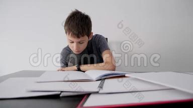 悲伤的孩子坐在桌子上，有许多书、笔记本和练习本。 男孩失望，因为他<strong>不明</strong>白