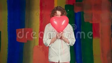 有趣的女孩带着红色的心脏气球。 美女带着五颜六色的气球笑在彩虹的背景上。