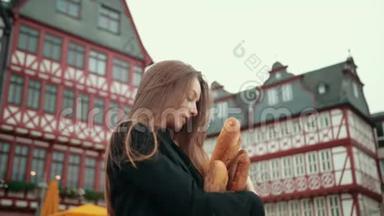 穿着黑色夹克衫的德国女孩笨拙地手底下拿着纸包的面包，