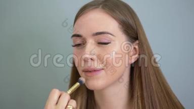 化妆师用画笔将<strong>粉底</strong>涂在女人的脸上。 沙龙