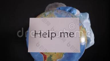 穿着防护服的女人拿着一个牌子，上面写着“帮助我”。 女孩拿着一个地球模型，一个地球仪。